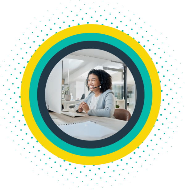 Smiling business professional using a headset and computer for office phone communication.